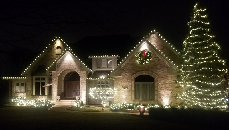 front of home at night lit by lights on trim and tree