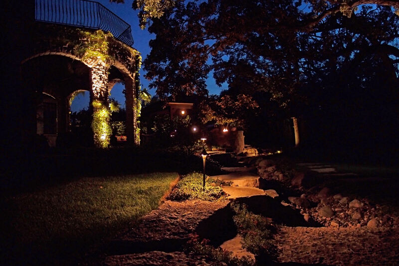 backyard being lit up by landscaping lights at night