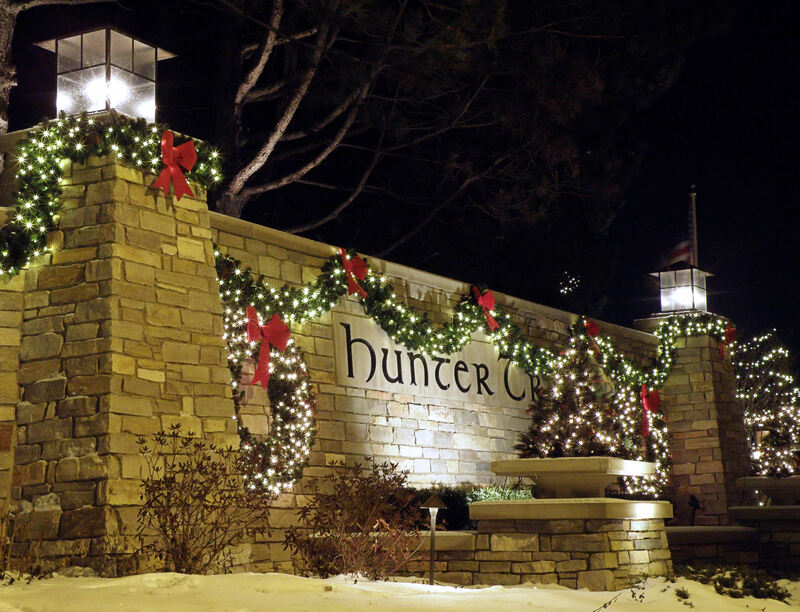 stone wall covered in wreaths and christmas lights