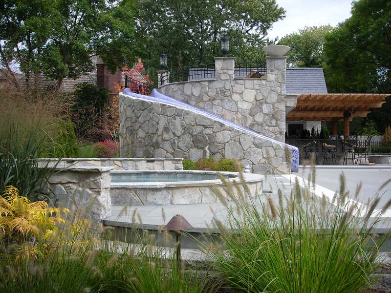 spiraling stone waterslide that leads to pool in backyard