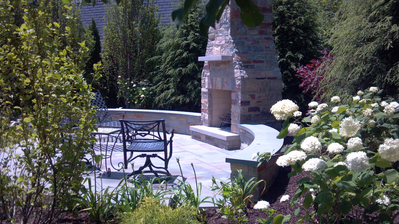 shot from garden of outdoor patio with furniture facing a fireplace and chimney