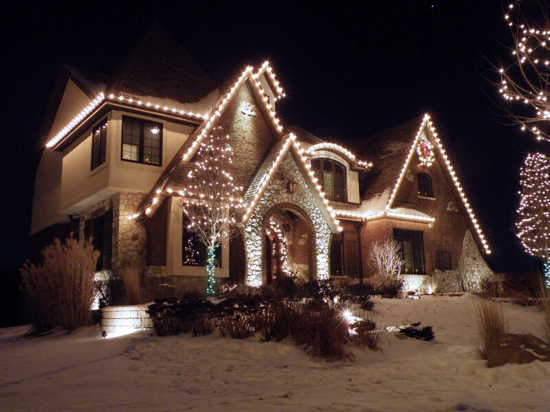 snow covered lawn and front of home with holiday lights