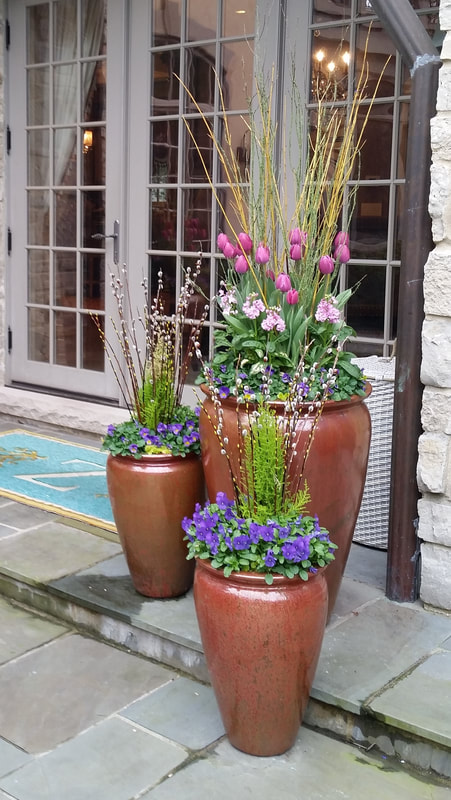 long copper flower pots with pink and purple flowers inside