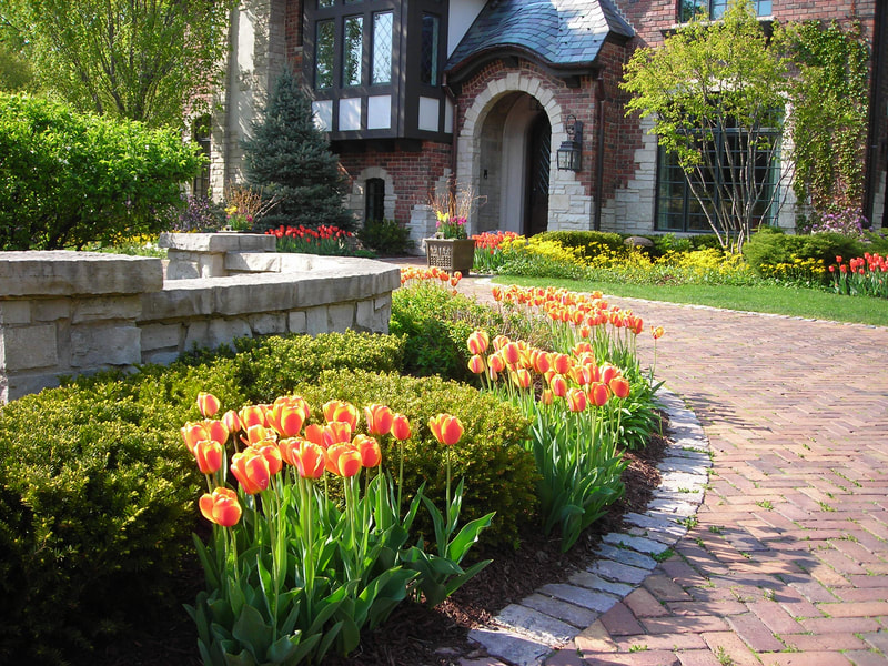 colorful flowers lining a brick driveway leading to mansion
