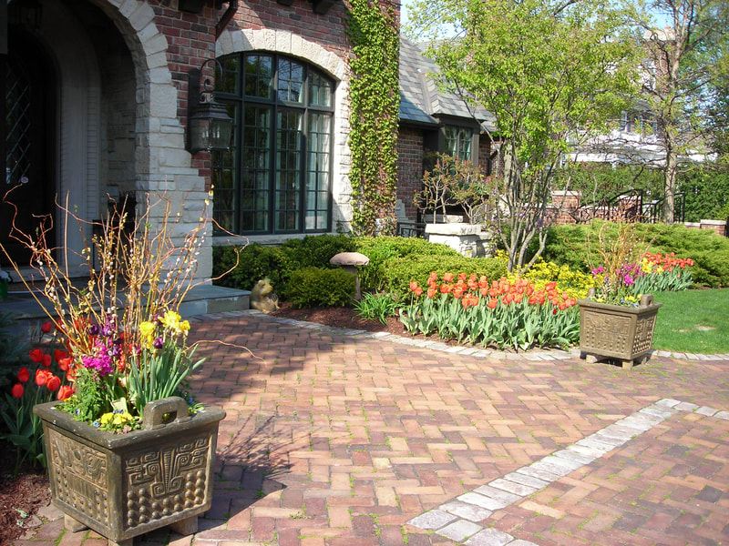 brick walkway to front door of mansion surrounded by shrubbery and flowers