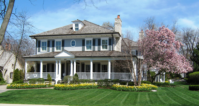 long shot of large house with manicured lawn and neatly planted yellow flowers